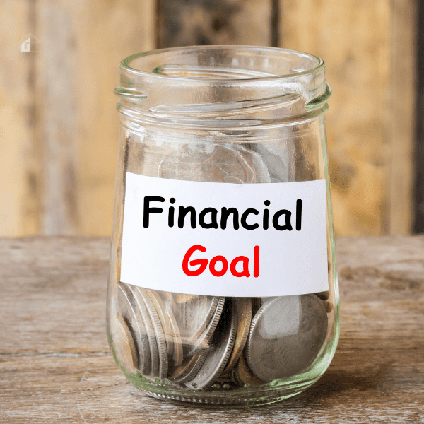 Small glass jar filled with coins and a sign of financial goal.