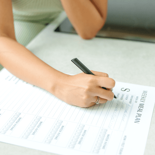 Woman writing down her meal plan.