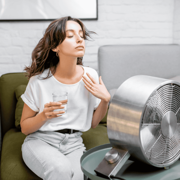 woman cooling off with a fan while drinking water.