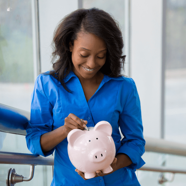 Woman putting money in her big pink piggy bank.