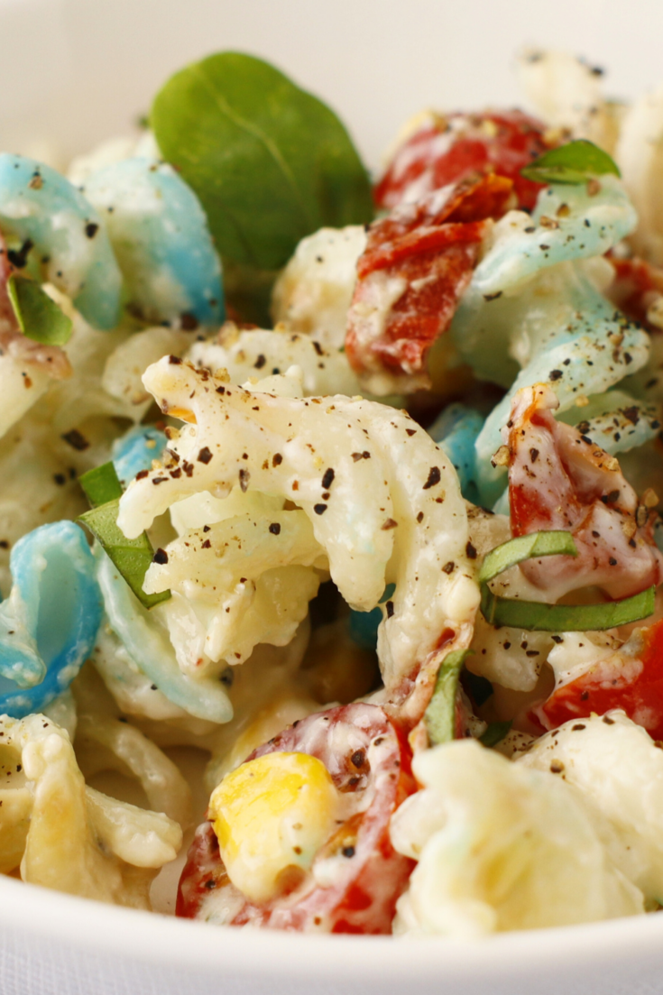 Creamy red, white, and blue pasta salad with bacon, bleu cheese dressing, sweet corn, and cherry tomatoes, perfect as an easy patriotic side dish for 4th of July summer BBQs.
