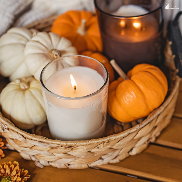 A cozy autumn basket centerpiece with small white and orange pumpkins surrounding glowing candles.