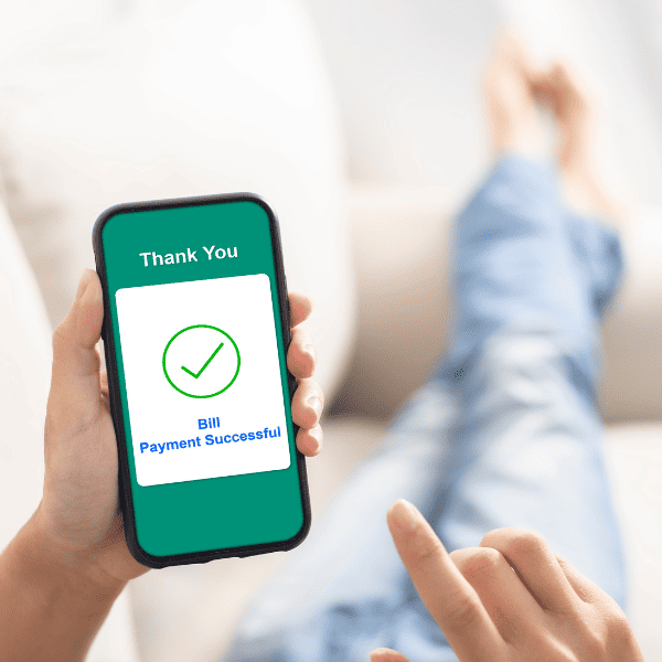Using smartphone banking online to pay bills at home.