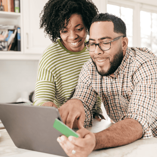 Couple paying bills online using a credit card and laptop.