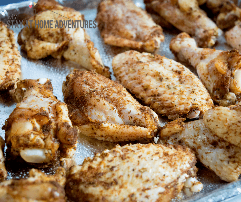 Raw chicken wing seasoned on baking sheet.