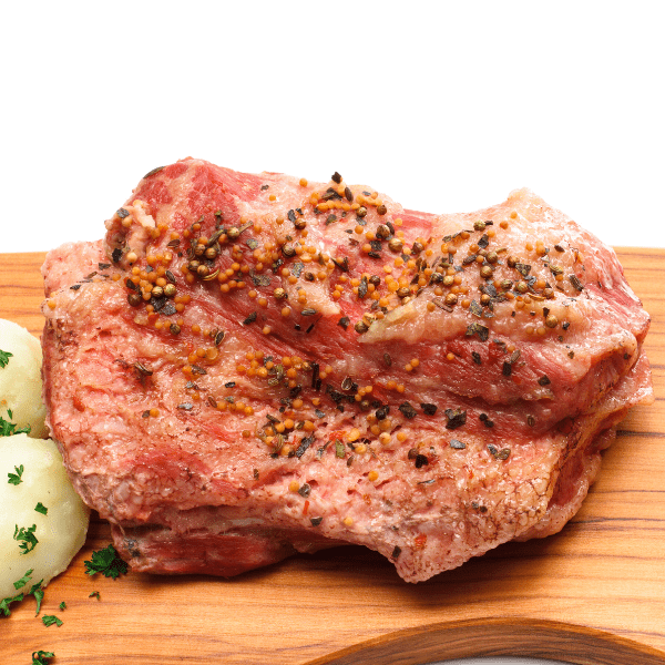 seasoned corned beef on wooden cutting board.