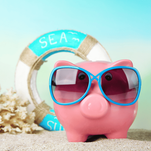 Piggy bank with sunglasses on the beach.