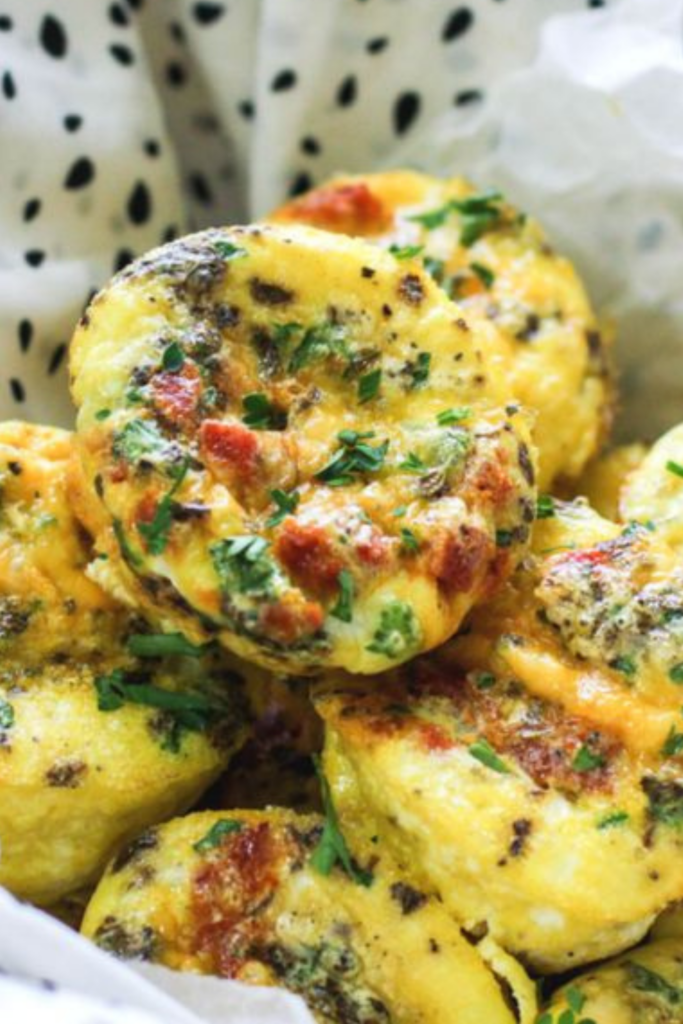 Golden chorizo and egg muffins topped with fresh herbs, served in a basket lined with parchment paper.