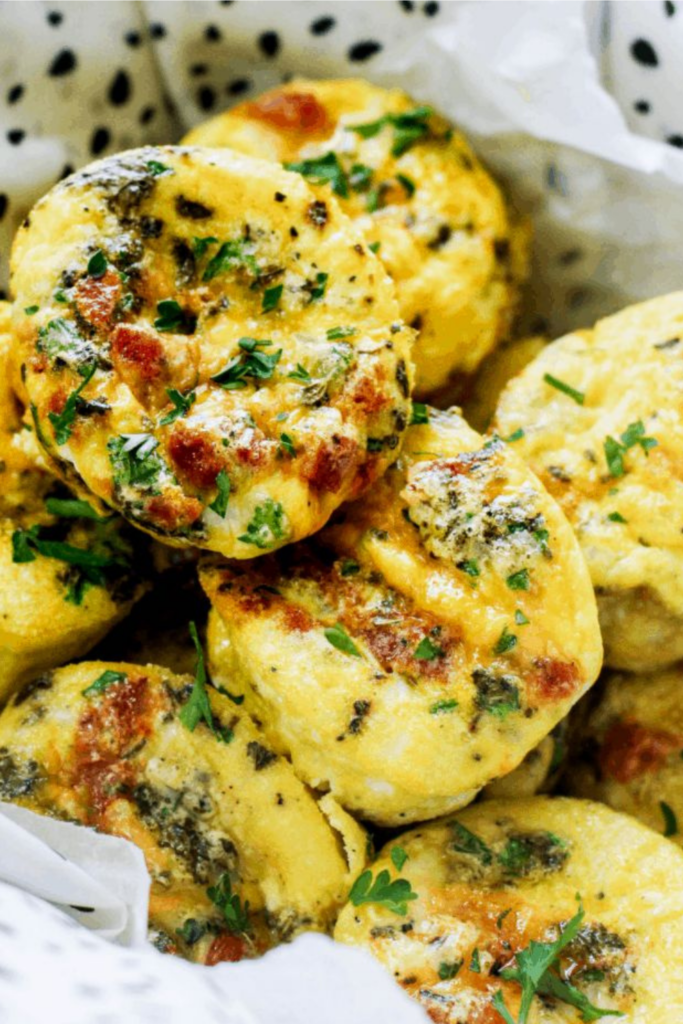 Freshly baked low-carb egg muffins with visible chunks of chorizo, melted cheese, and herbs.