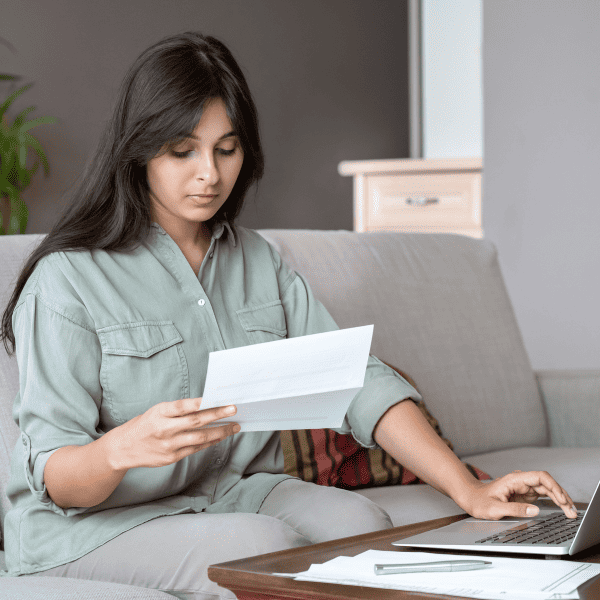 Woman holding a letter and using a laptop computer.