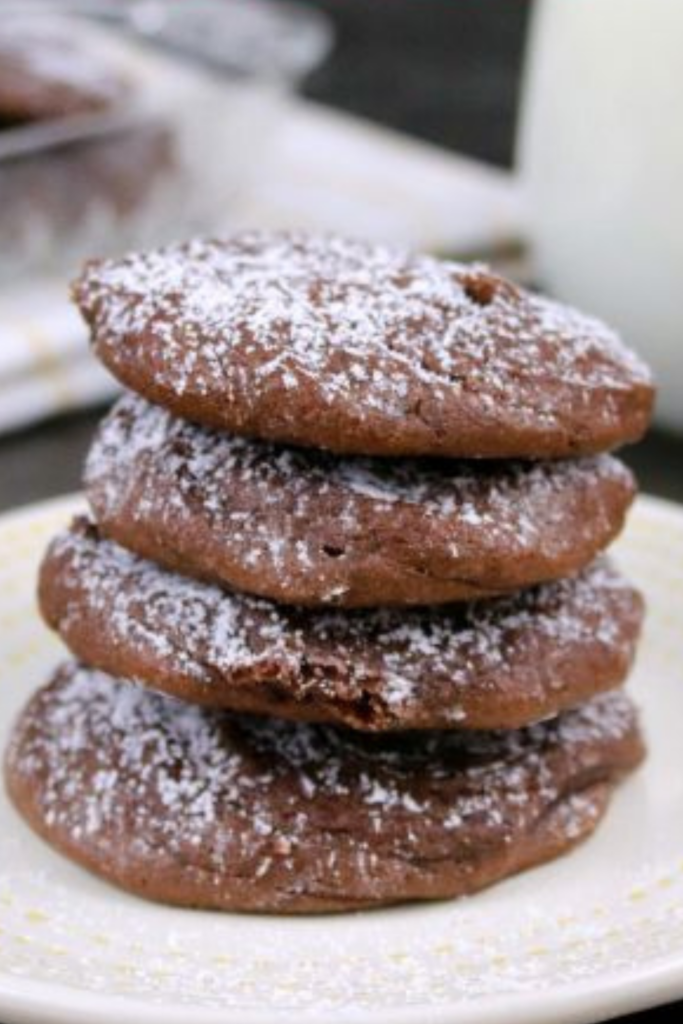 A stack of Sea Salt & Caramel Nutella Cookies dusted with powdered sugar on a dessert plate.
