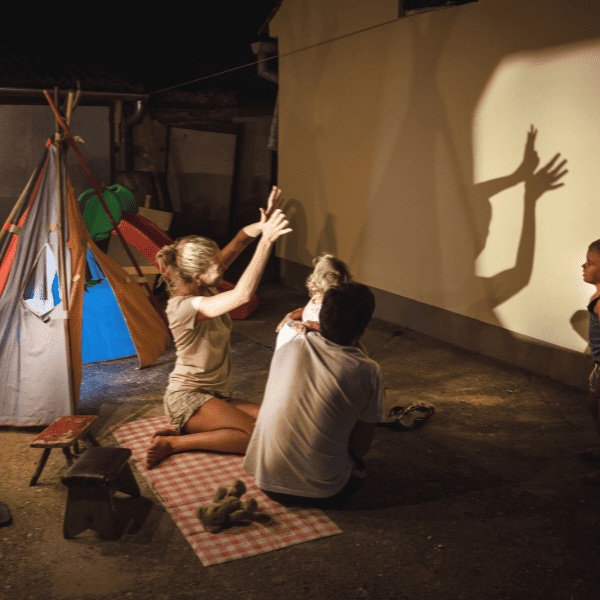 Family camping in their backyard playing with shadows.