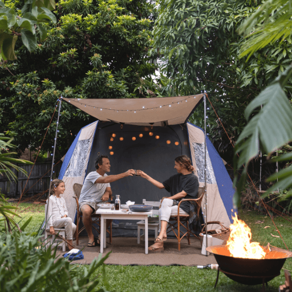 Parents cheers over a glass of wine whil camping in theri backyard.