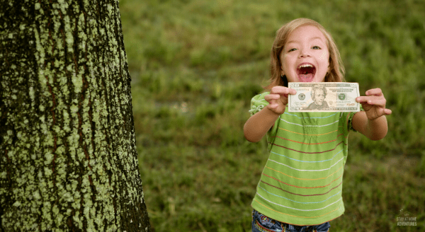 little girl holding a twenty dollar bill.