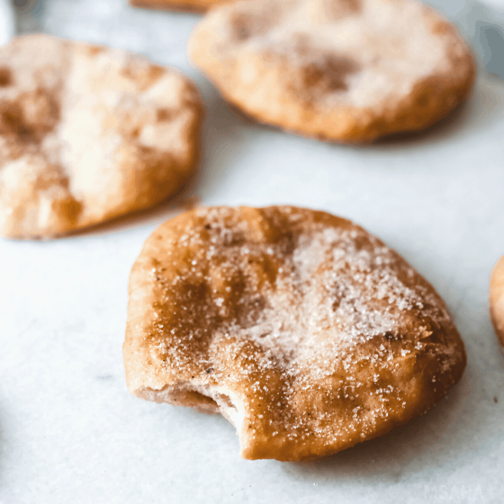 Three Mexican Buñuelos and the front one is eaten.