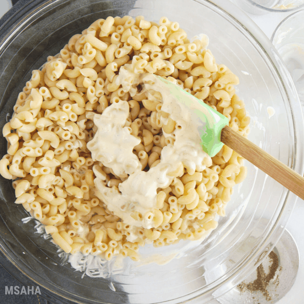 Photo of pasta with the dressing combined in a glass bowl.