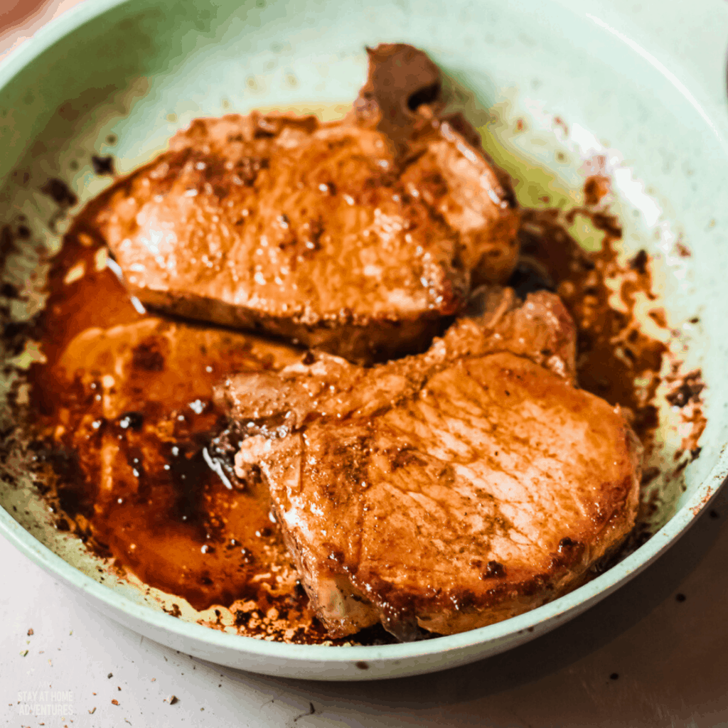 photo of two fried pork chops in pan