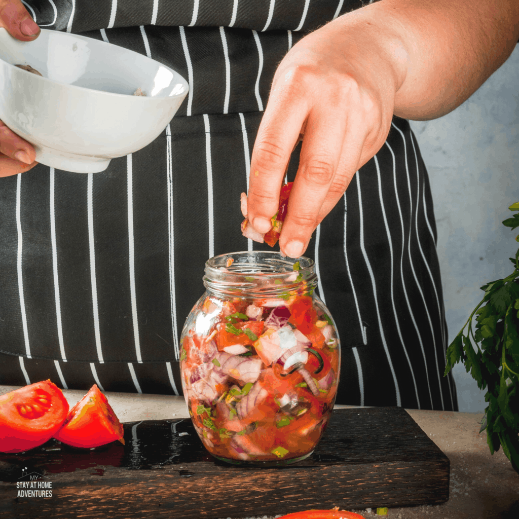 Woman canning salsa in a jar.