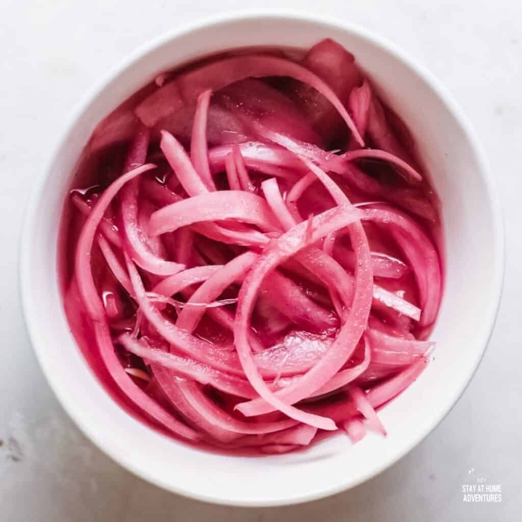 Photo of pickled red onions in a white dish.