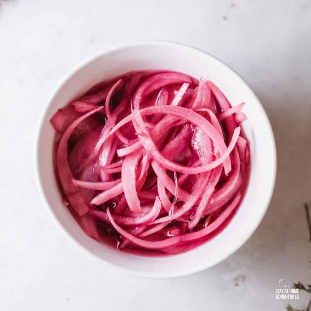 Photo of pickled red onions in a white dish.