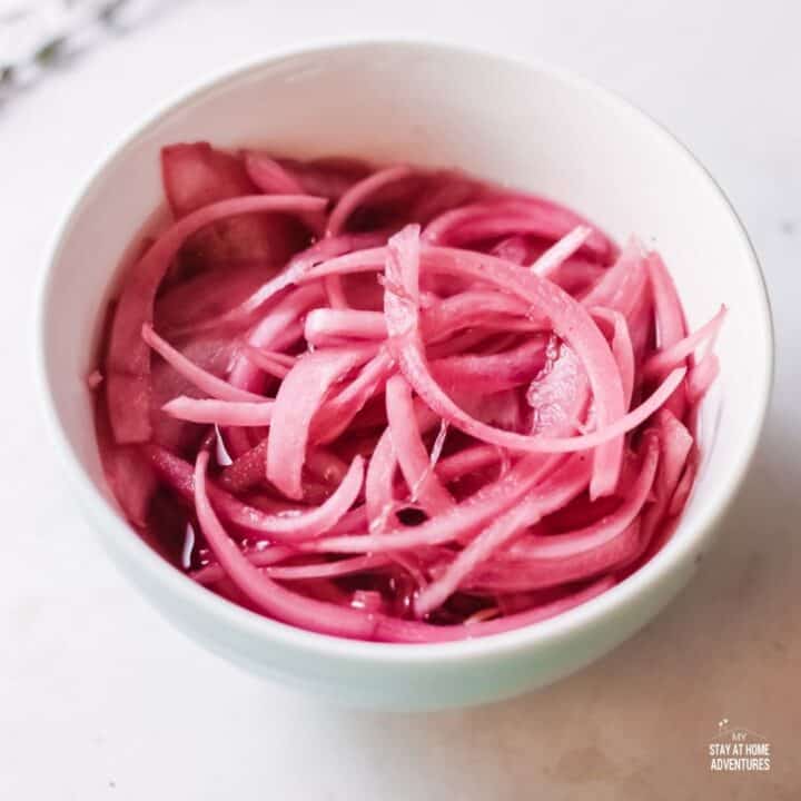 sliced pickled red onions in a white bowl.