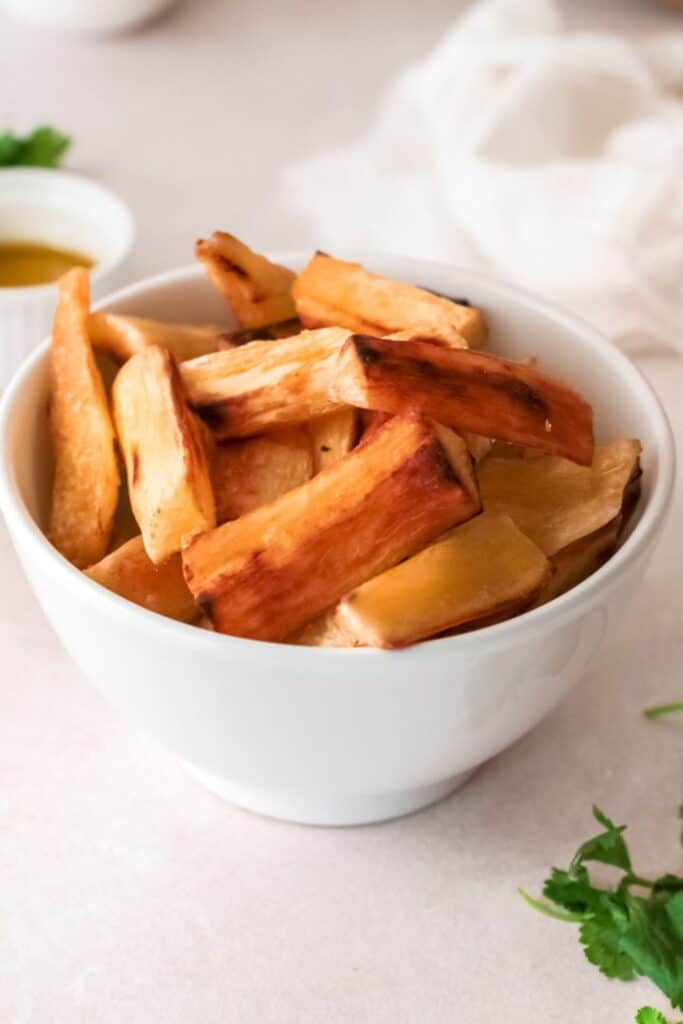 Close up photo of yuca fries served in a white bowl.
