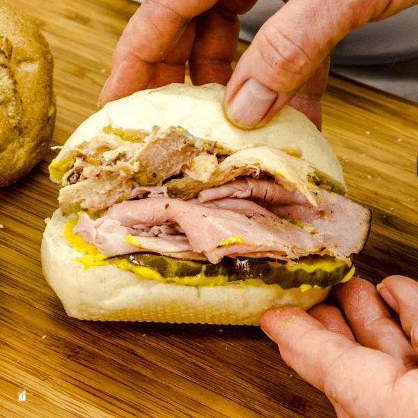 photo of men holding a medianoche sandwich