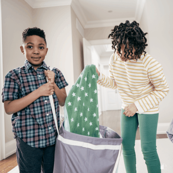 photo of two kids carrying a laundry bag and one pulling a green towel out.