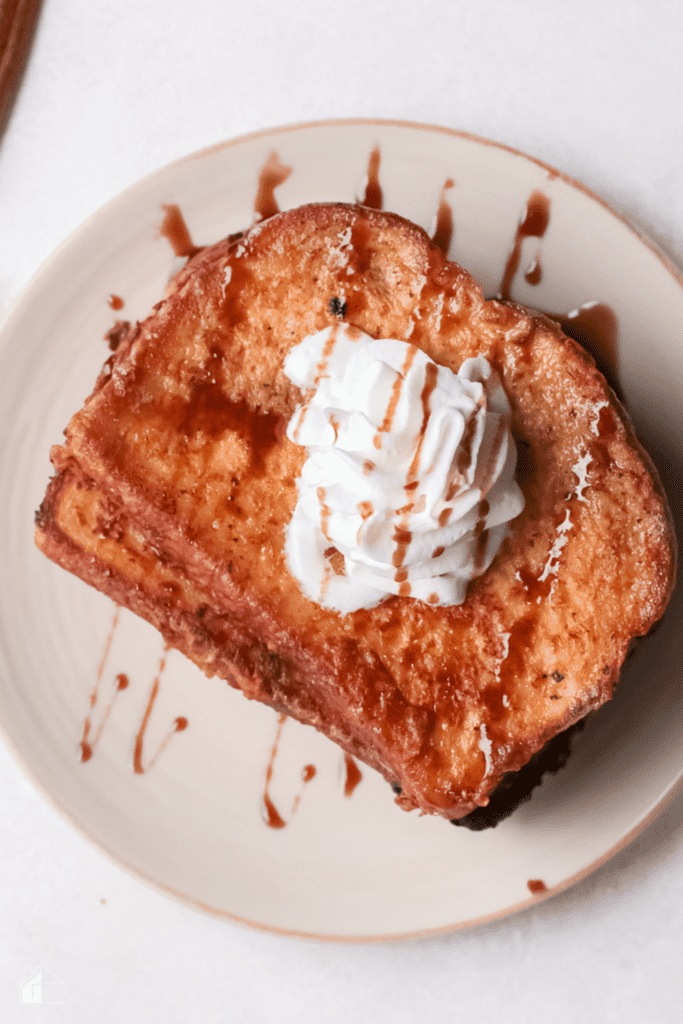 Top view of eggnog french toast palted with whop cream and caramel ontop.