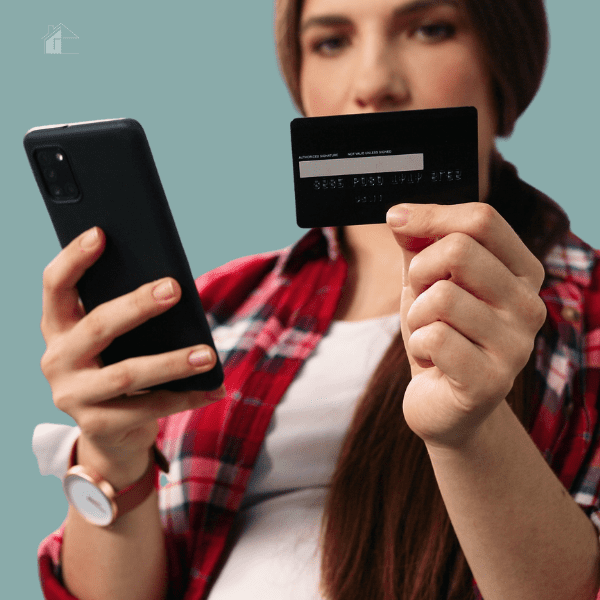 Young brunette holding a credit card and a smart phone.