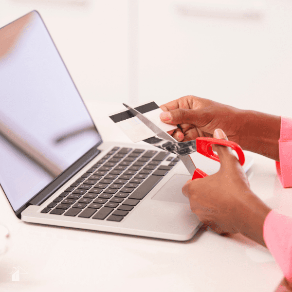 Close up woman's hands in pink pajamas sleeves cutting credit card to reduce online expenses.