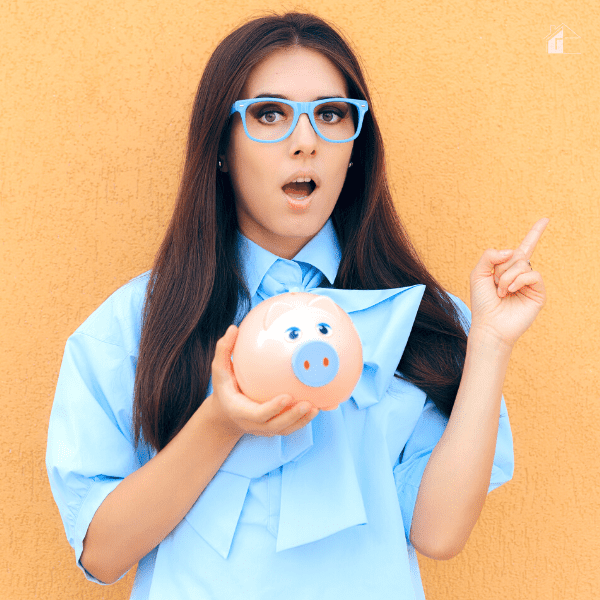 Female holding a piggy bank and pointing to the side.