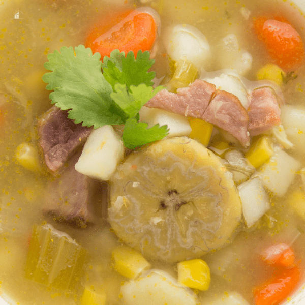 Close up photos of ham and plantain soup with potatoes, corn and carrots.