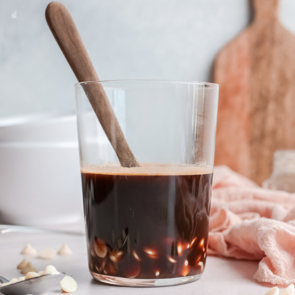 white chocolate and coffee inside a glass with a wood mixer