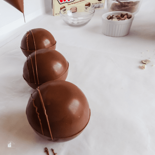 Dripping remaining hot chocolate on top of chocolate bombs.