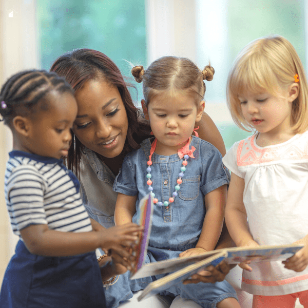 Caregiver with three toddlers reading a book.