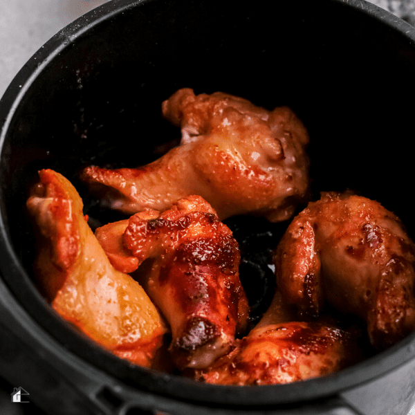 cooked chicken wings in an air fryer basket.