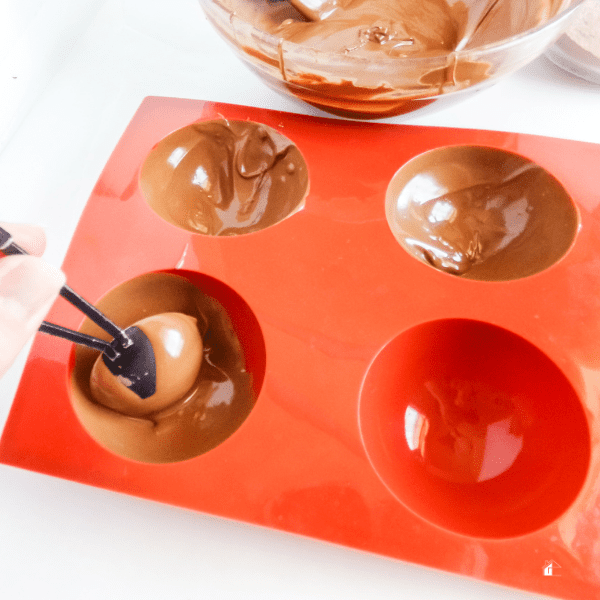 woman hands pouring melted chocolate in mold.