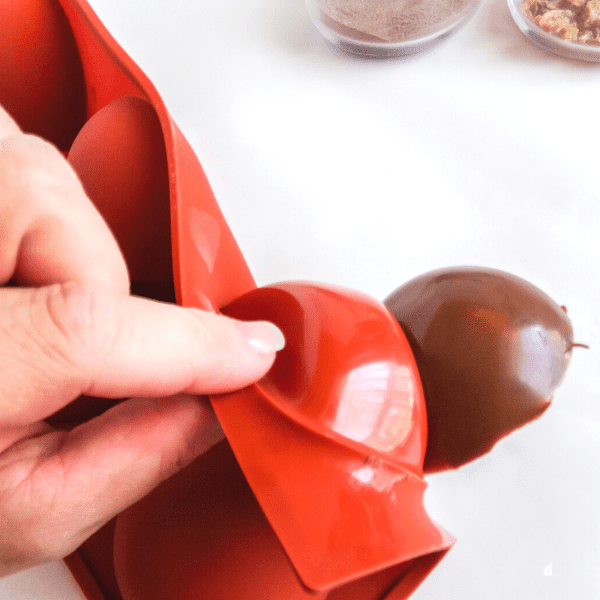 gently peeling the silicone mold away from the chocolate cups