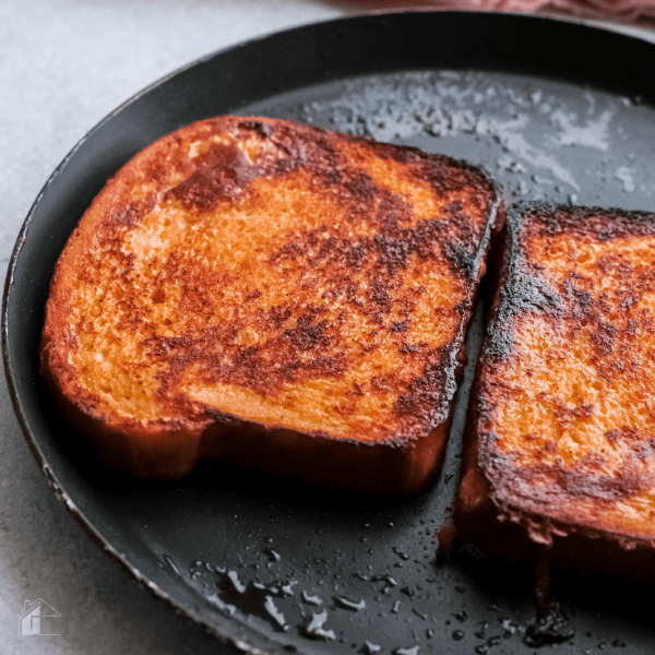 two french toast cooking in a skillet