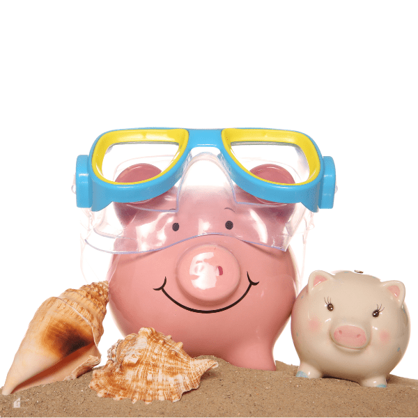 two piggy banks one wearing water googles next to sea shells and standing on sand.