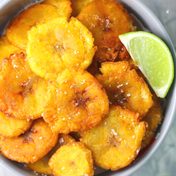 Close up of a small bowl of tostones with a lime on top.