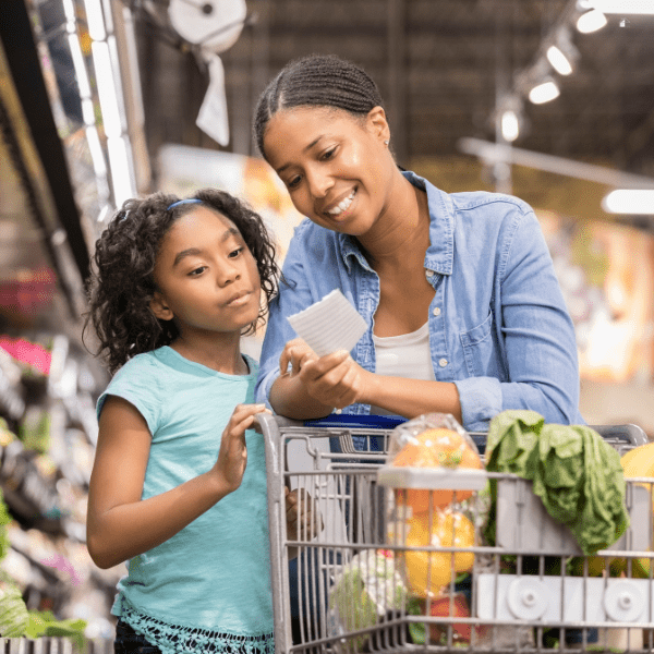 Mother and daughter grocery shopping using a shopping list.