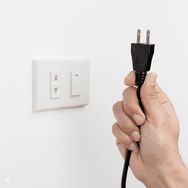 Female hand unplugging a cord from a wall.