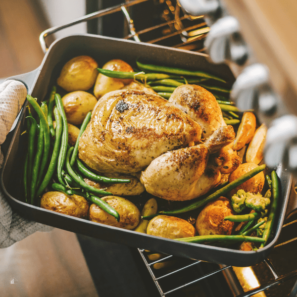 Cook taking ready chicken from the oven