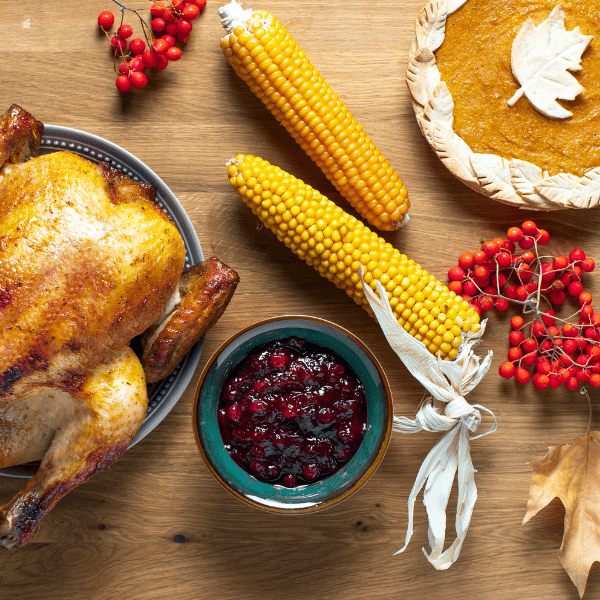 Thanksgiving dinner food , turkey, two corn on a cob, apple pie.