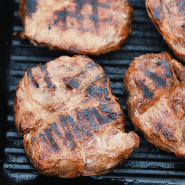 Close up of pork steaks grilling.