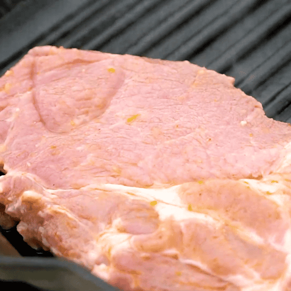 Raw pork steak on a grill.