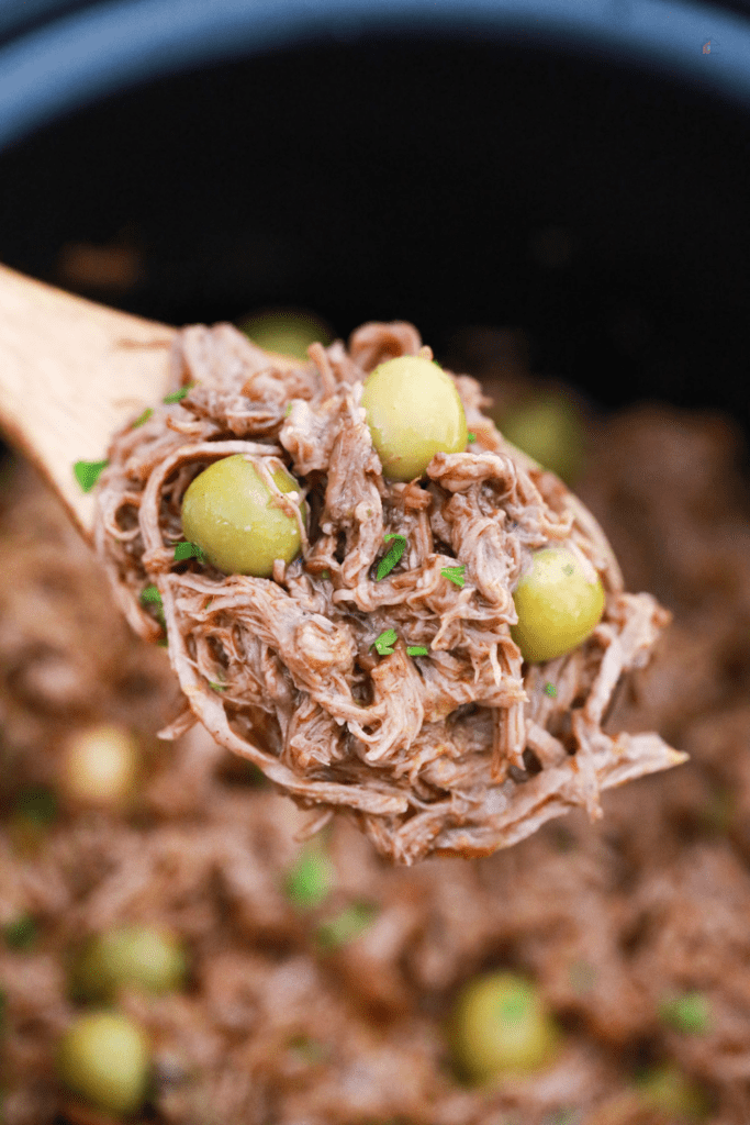 Wooden spoon holding shredded beef.
