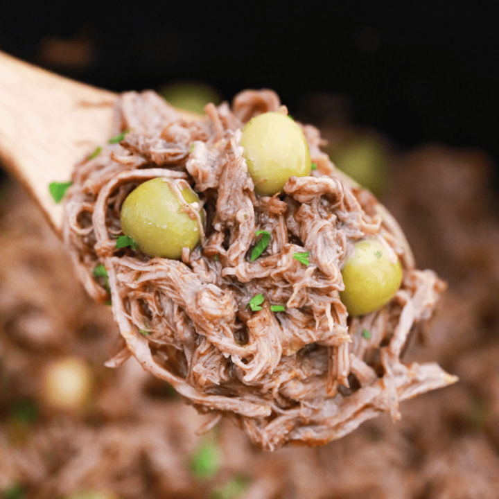 Wooden spoon holding shredded beef.